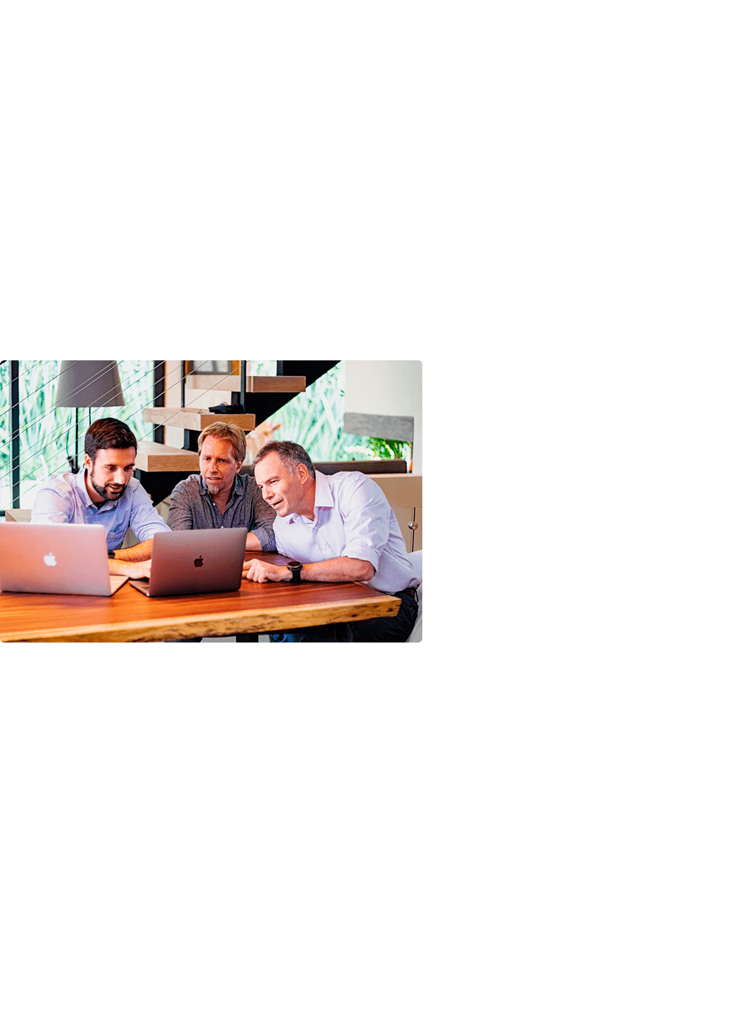 Photo of three people working with computers in a modern building